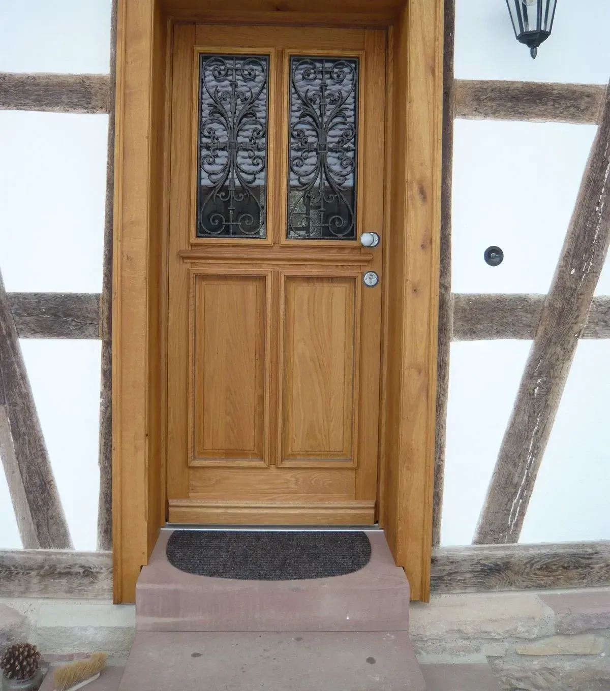 Haustür aus geölter Eiche mit schmiedeeisernen Ziergittern in einer Fachwerkfassade