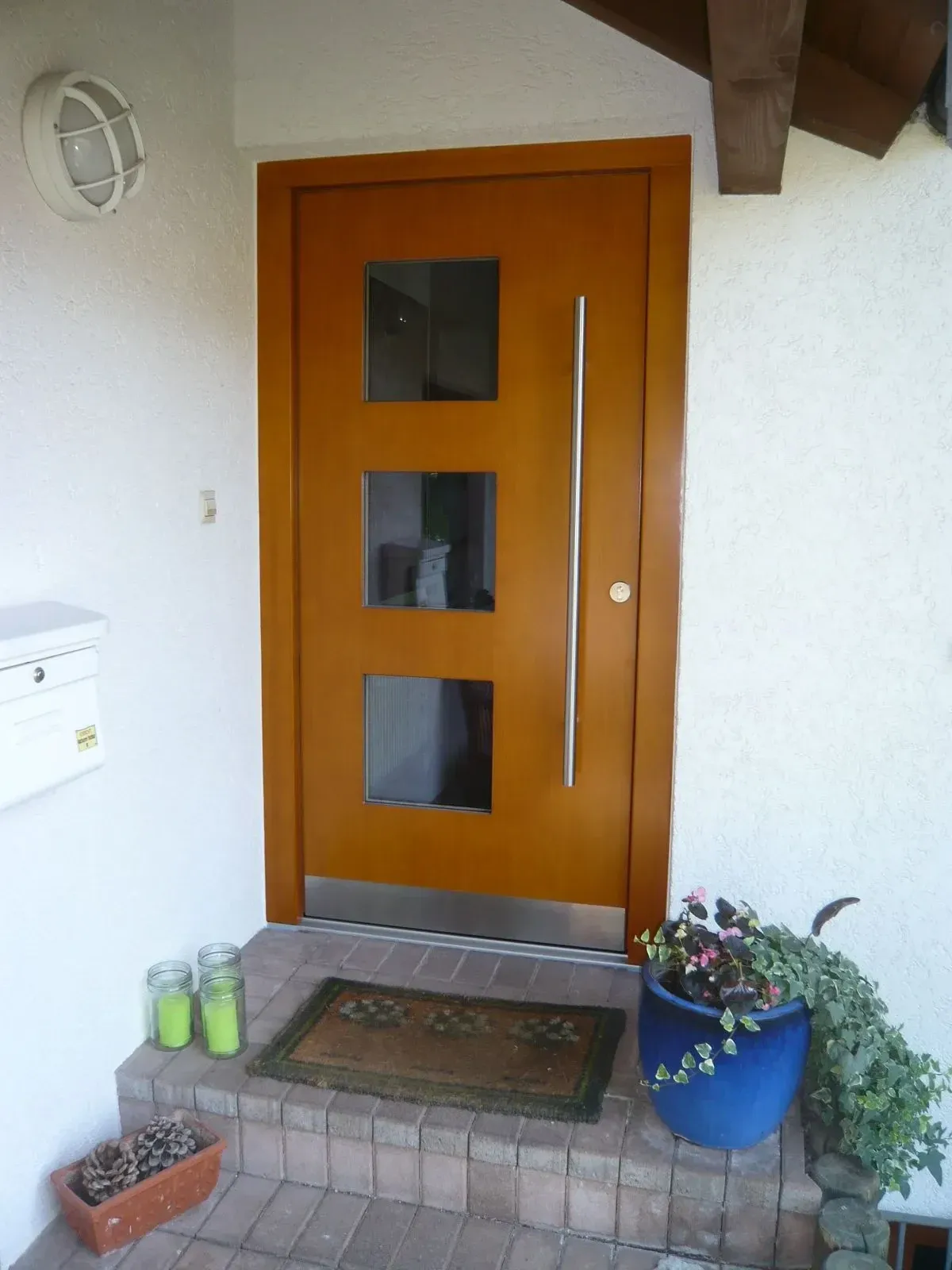 Moderne Holzhaustür mit drei quadratischen Glasausschnitten und Edelstahlgriff