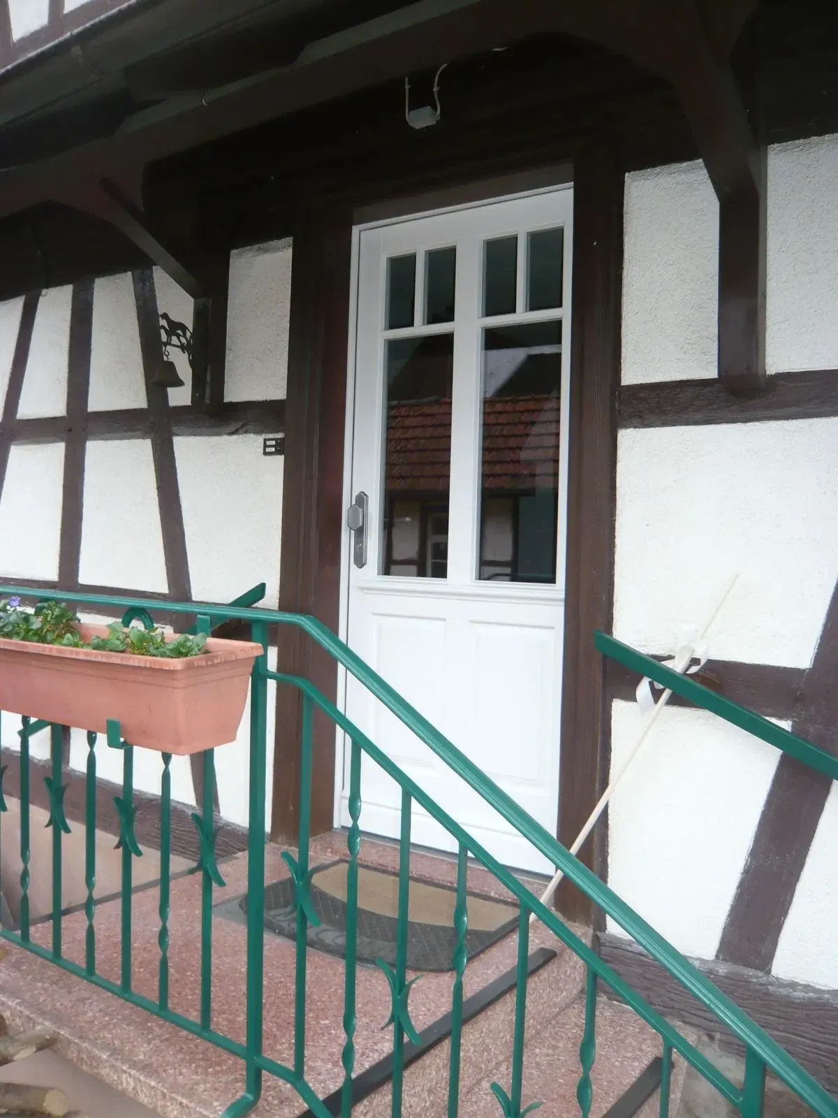 Weiße Holzhaustür mit Sprossen an einem Fachwerkhaus mit Treppenaufgang