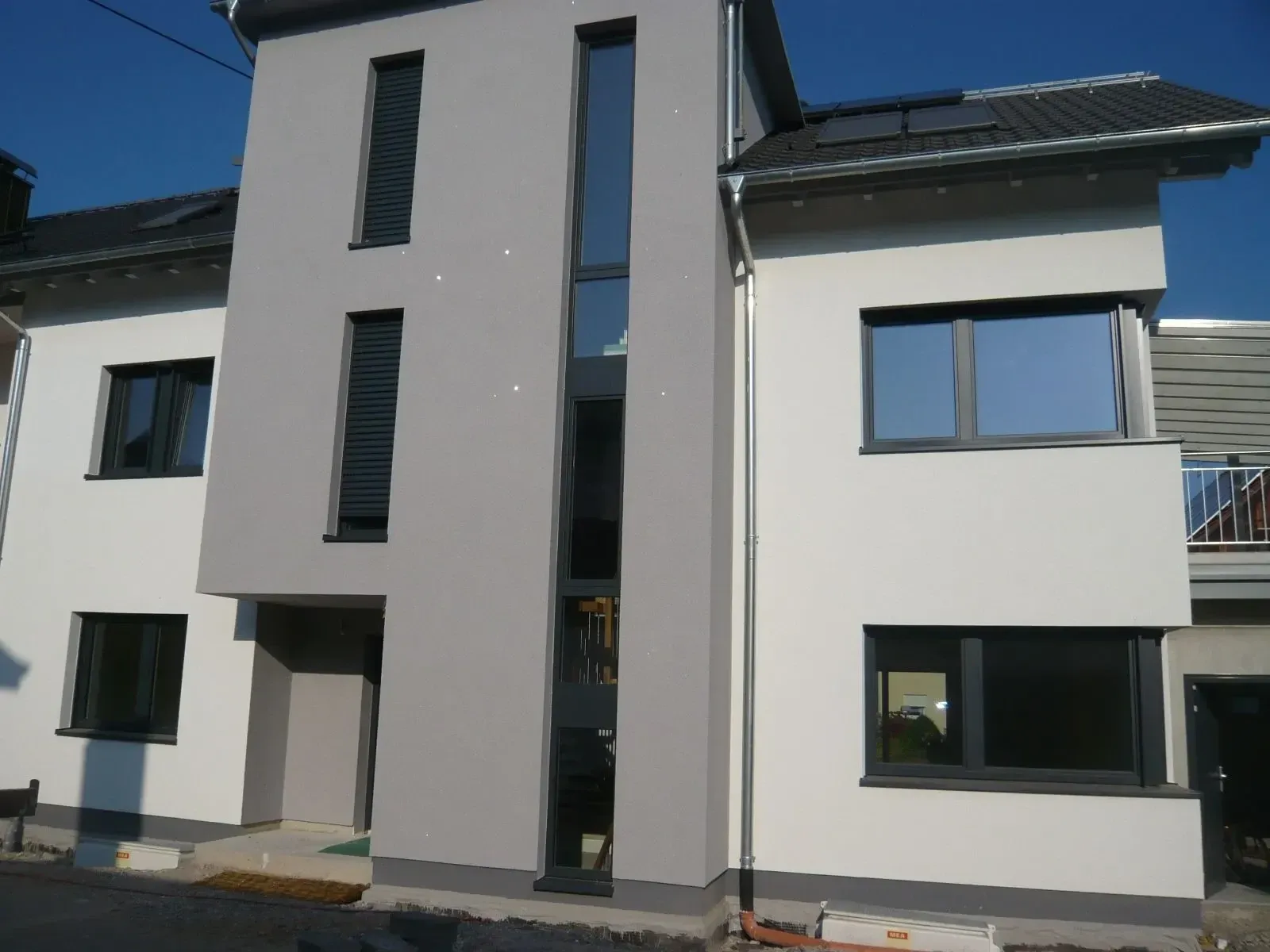 Neubau mit anthrazitfarbenen Holz-Alu-Fenstern und schmalen Fensterbändern