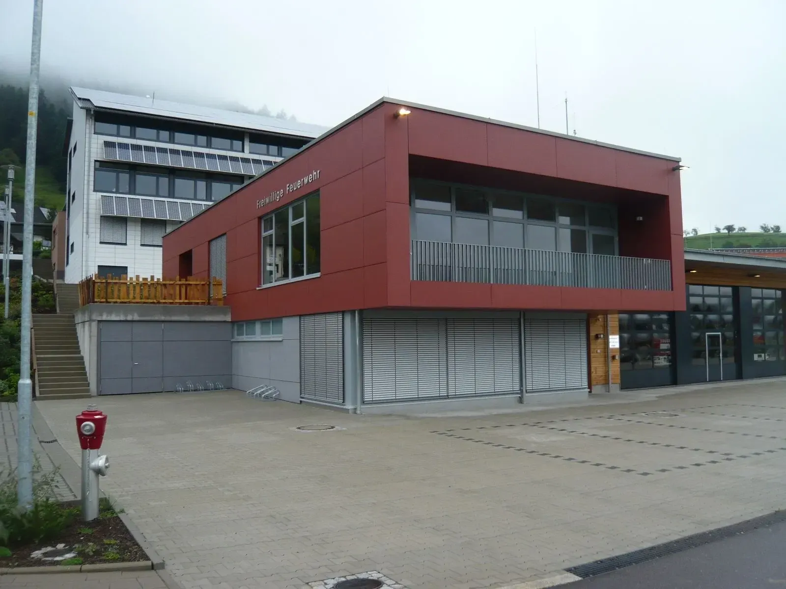 Moderner öffentlicher Neubau mit roter Fassade und großen Fensterflächen