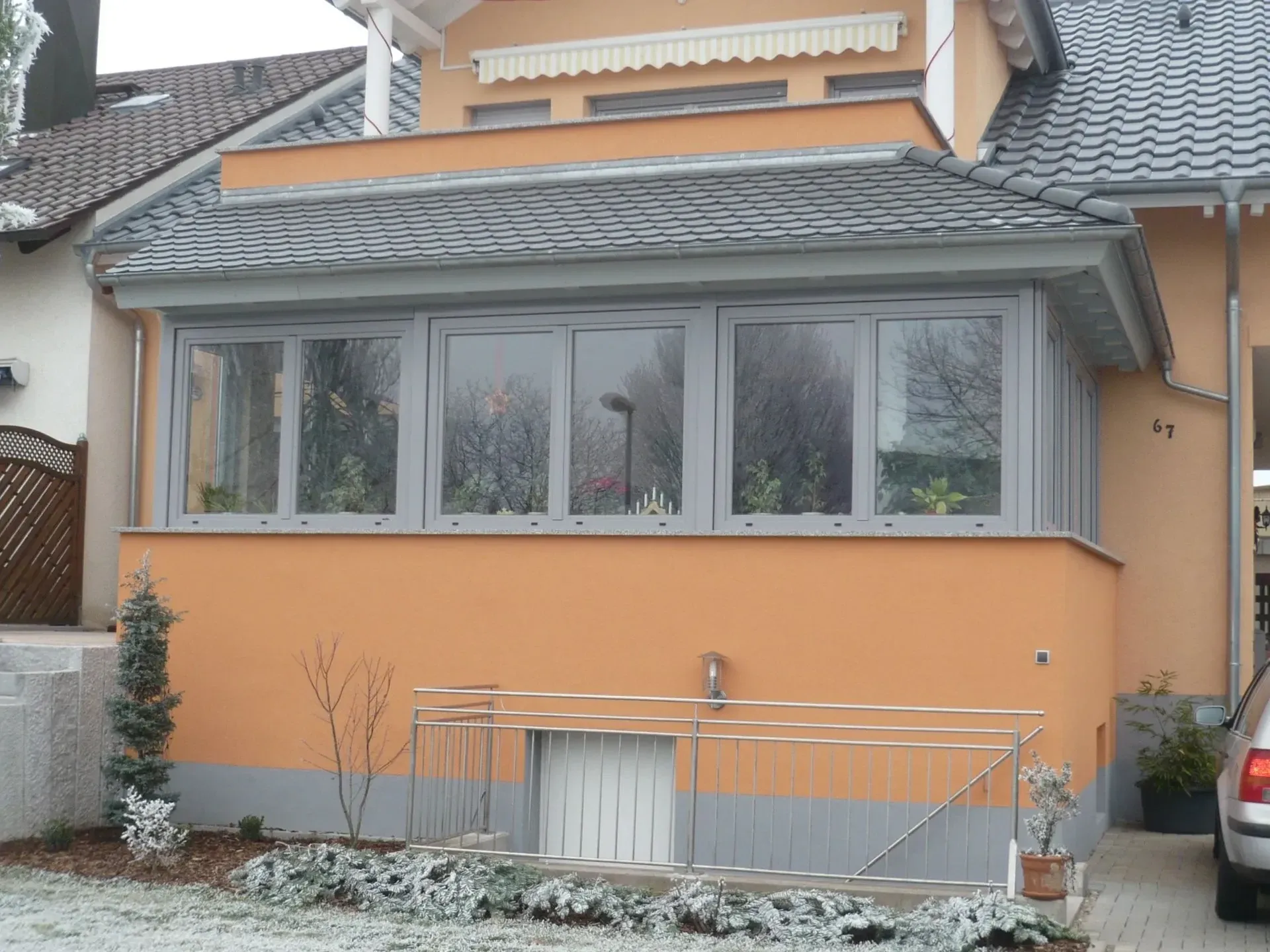 Wintergarten-Anbau mit grauen Rahmen an einem Einfamilienhaus