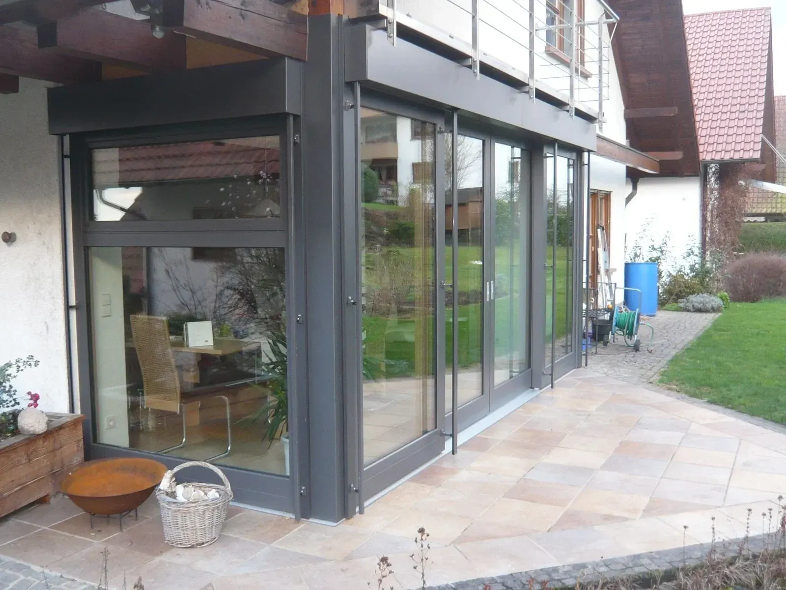 Wintergarten mit anthrazitfarbenen Profilen und großen Schiebetüren zur Terrasse
